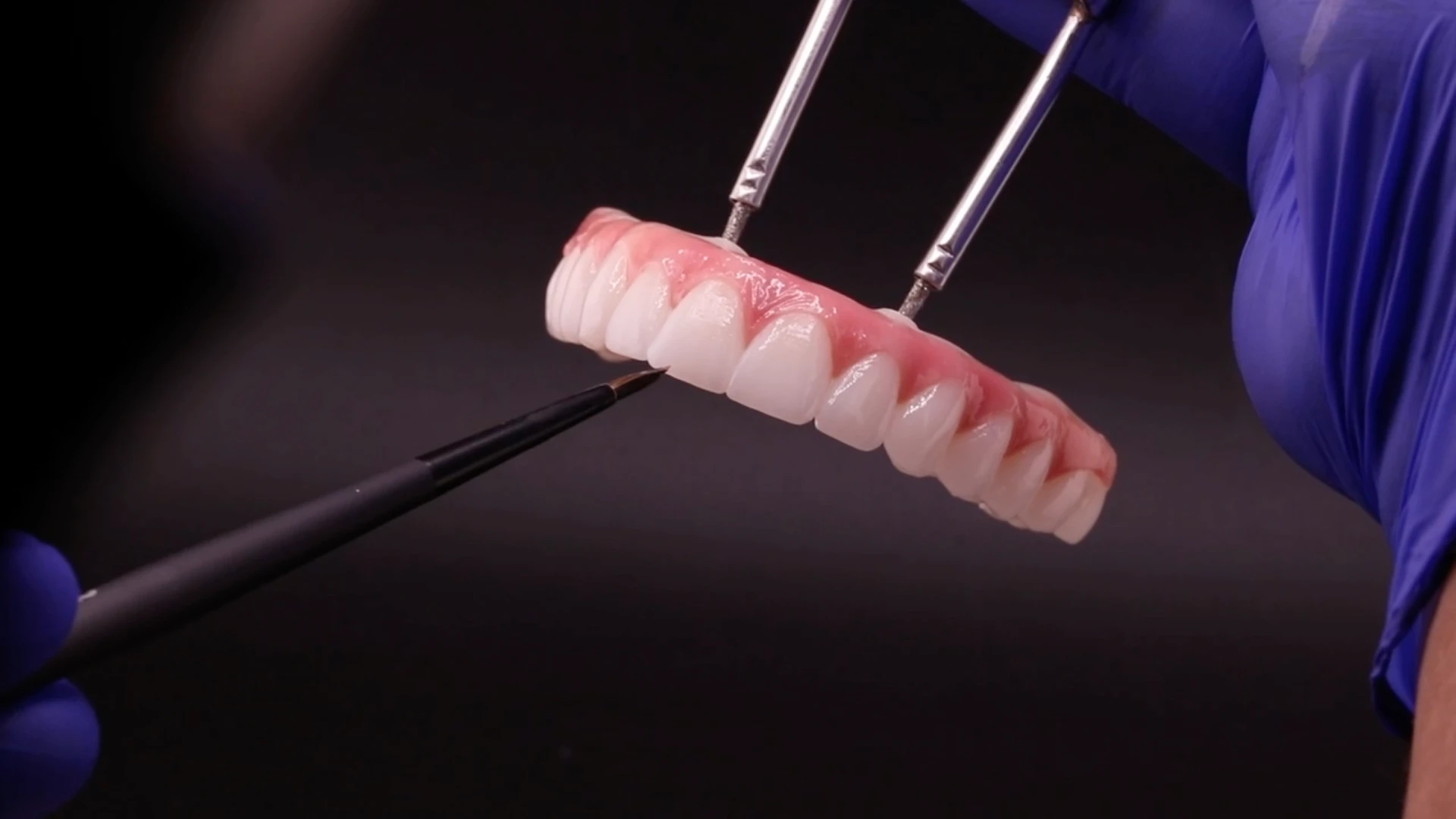 dental lab technician painting final all-on-4 implant bridge